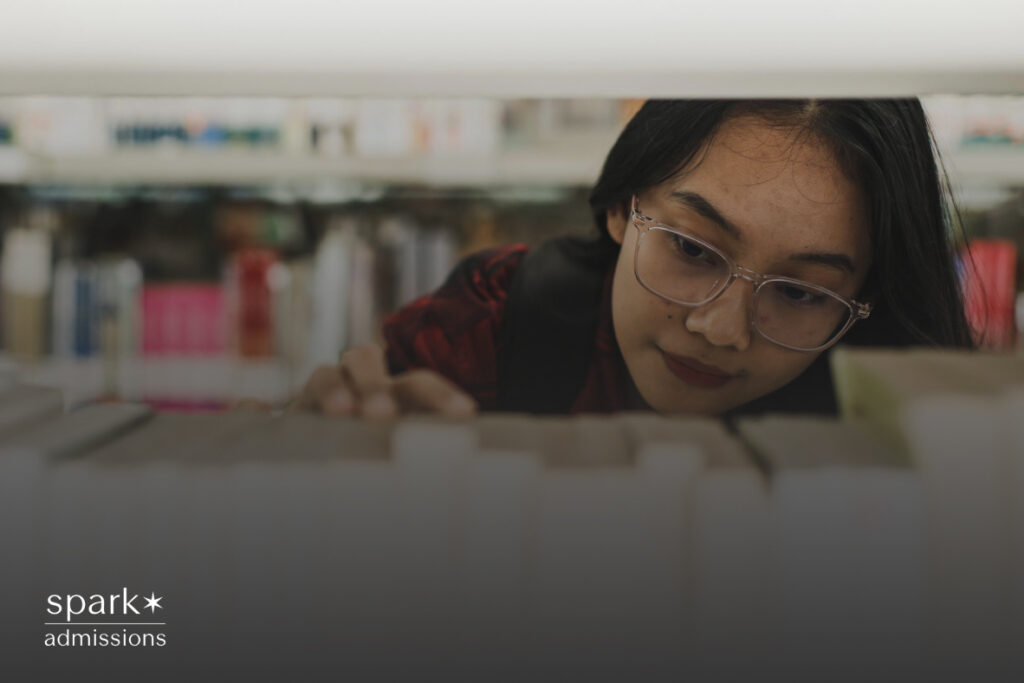 An Asian woman student in a library, intently scanning the shelves for a book, with a focused expression, surrounded by rows of books and a quiet, studious atmosphere.