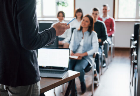 A group of students seated in a classroom, attentively listening to a lecture or working on an assignment, with books, notebooks, and laptops on their desks, creating an active and collaborative learning environment.