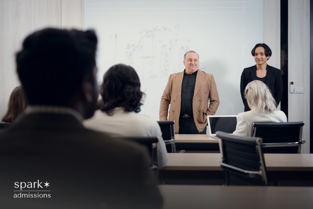 Professor and student presenting in a room with a whiteboard graph in the background