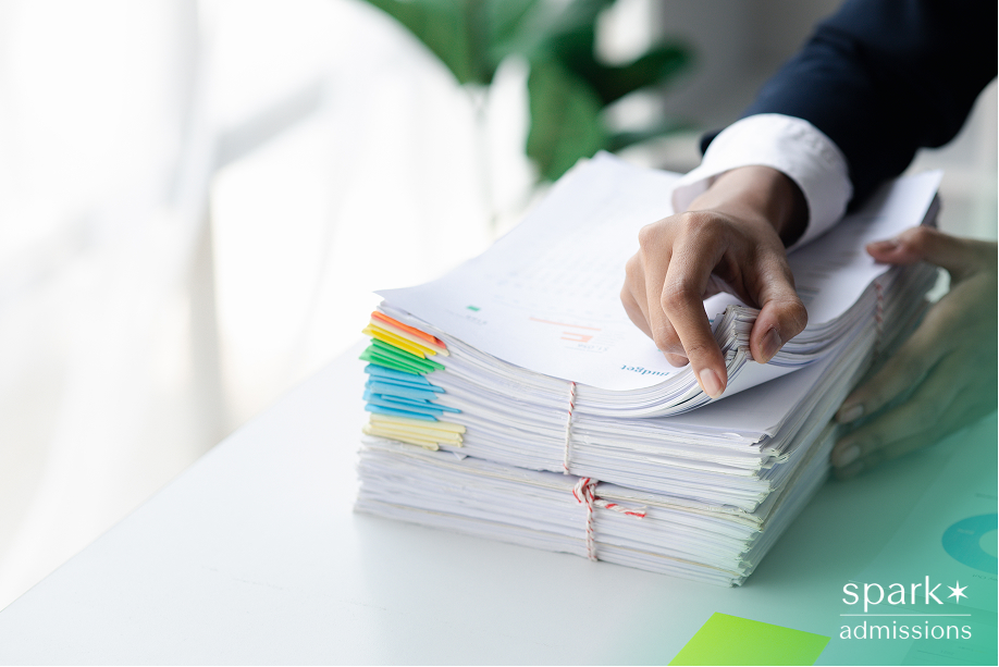 Close-up of hand flipping through a tall stack of organized paperwork with color-coded tabs